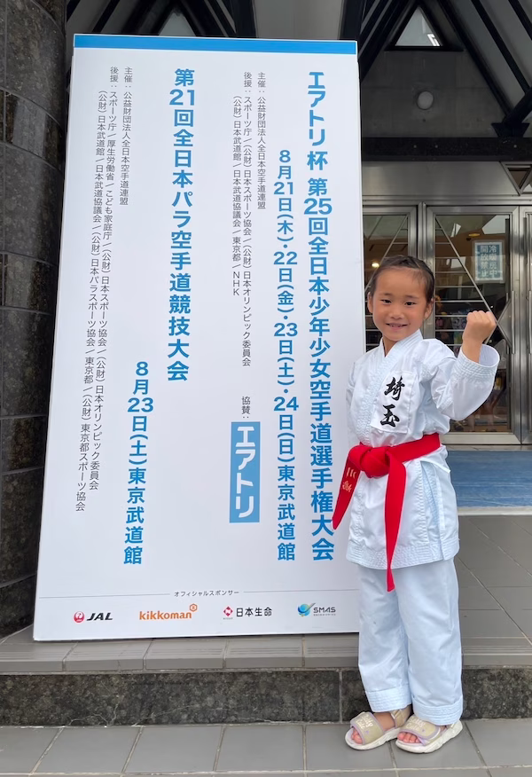 大会サイネージの前でポーズをとる川嶋凛希さん